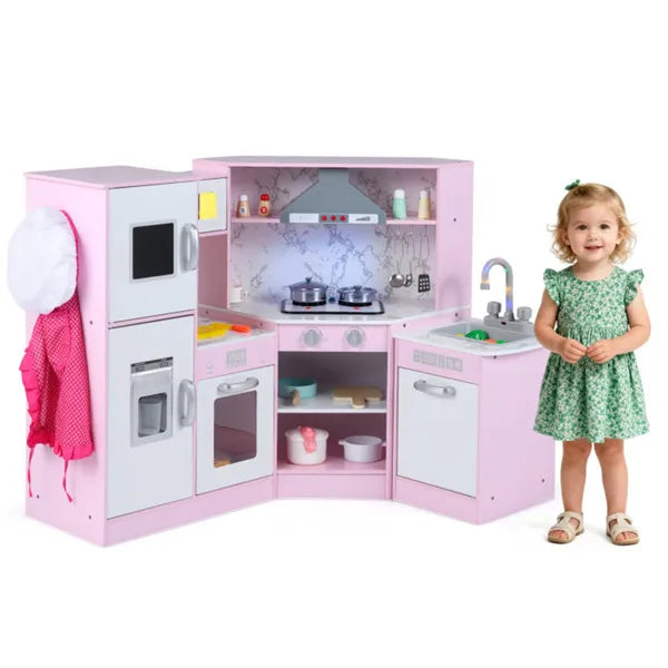 Pink toy kitchen set with a child in a green dress standing next to it on a white background