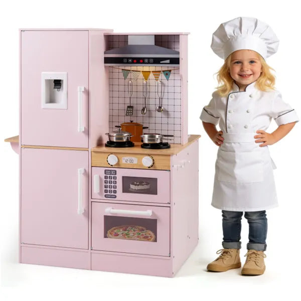 Child in a chef's outfit standing next to a pink toy kitchen set