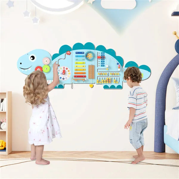 Children playing with a dinosaur-shaped educational wall chart in a room.
