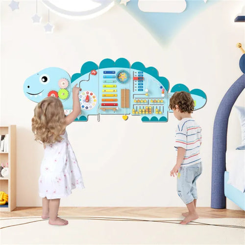 Children playing with a dinosaur-shaped educational wall chart in a room.
