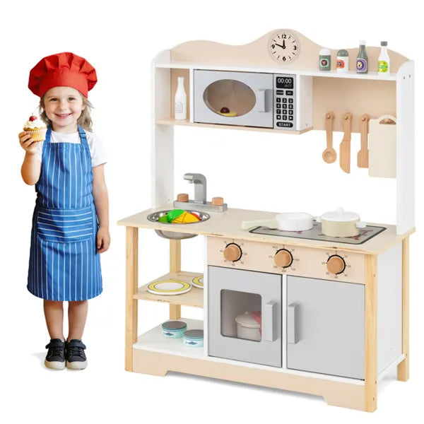 Child in chef attire standing next to a wooden play kitchen set