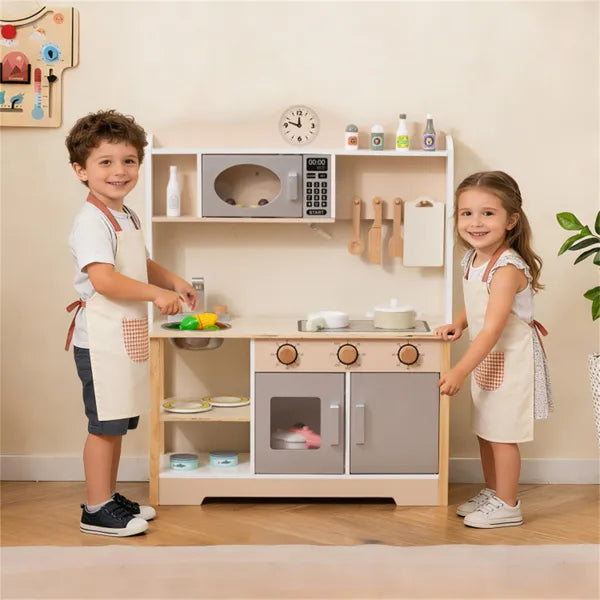 Two children playing with a toy kitchen set in a room.