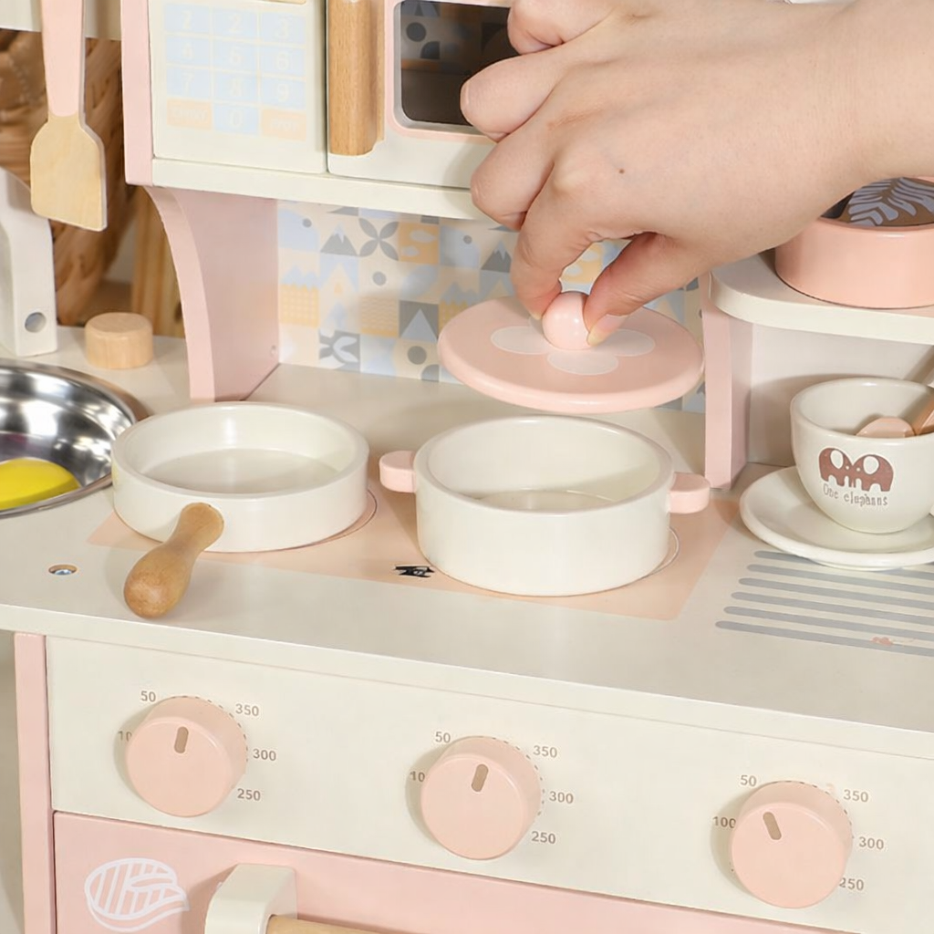 Children's play kitchen set with a hand interacting with a toy stove and pots.