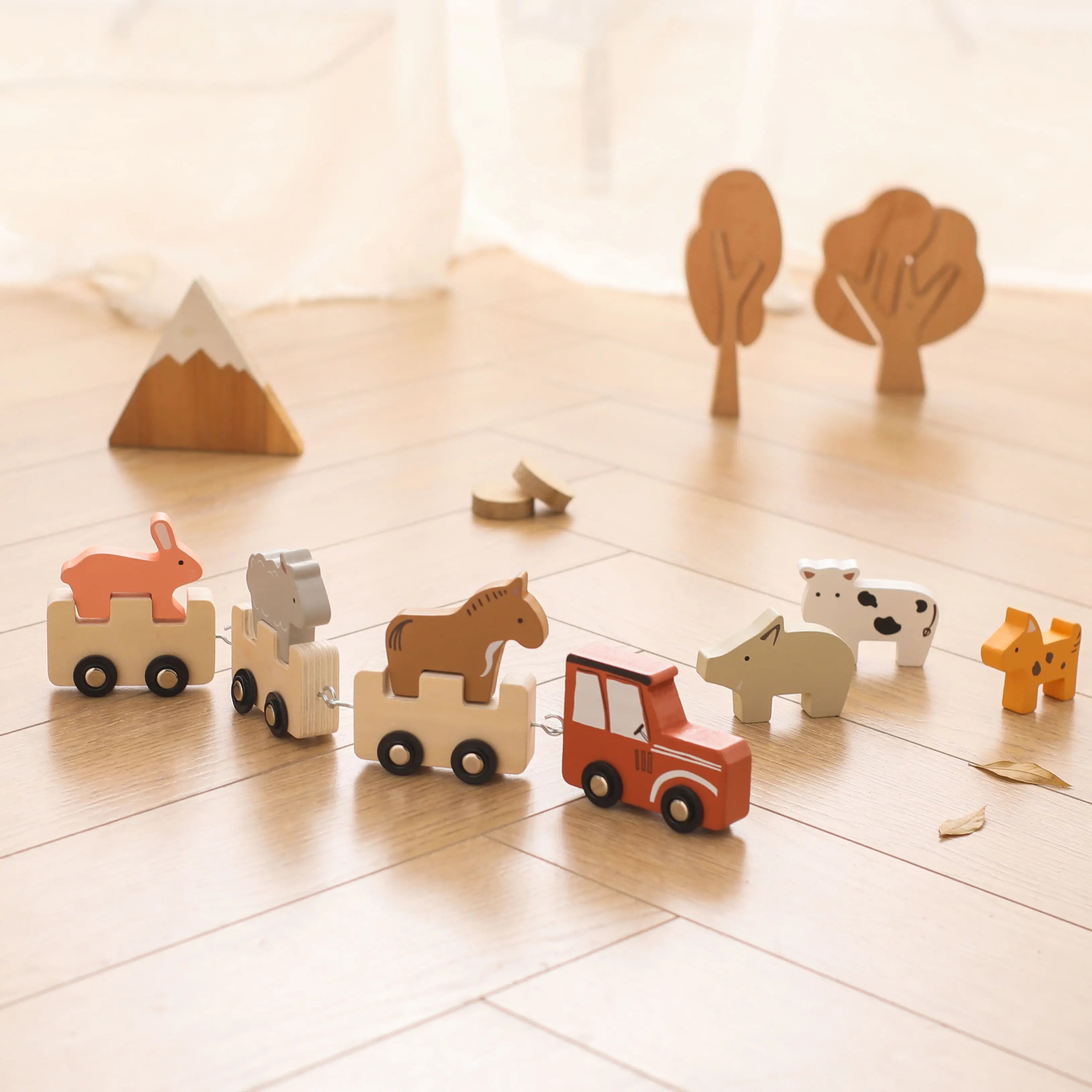 Set of wooden animal toys on a light wooden floor with small trees in the background.