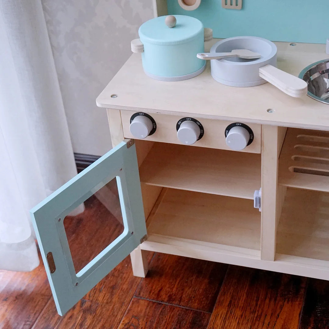 Wooden play kitchen set with toy pots, pans, and a microwave on a wooden floor.