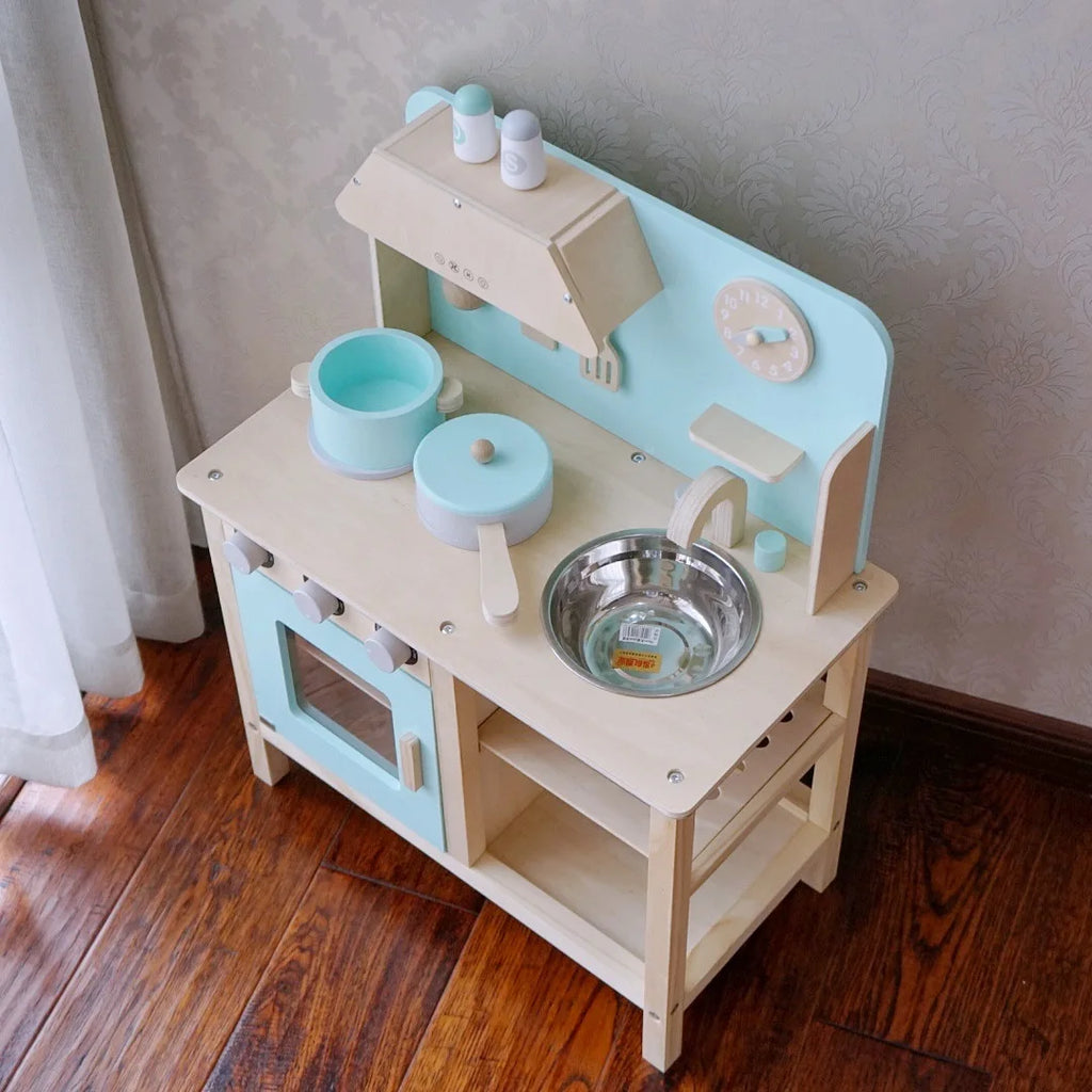 Children's wooden play kitchen set with accessories on a wooden floor.
