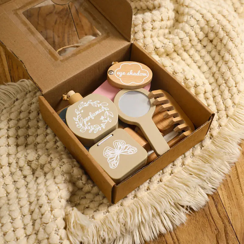 Set of wooden makeup items including a mirror, brush, and containers in an open cardboard box on a textured surface.