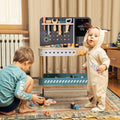 Two children playing with a toy tool set and workbench in a room.